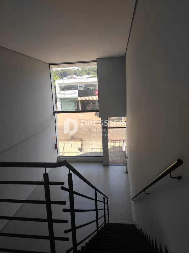 Corredor com escada e paredes brancas.