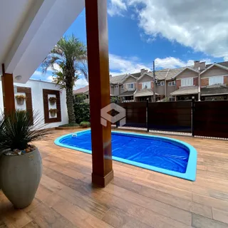 Foto da área externa com piscina e deck de madeira.