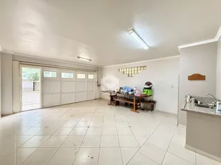 Interior de uma ampla sala com porta de garagem e piso de cerâmica clara.