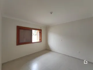 Imagem de um cômodo interno com paredes brancas e uma janela de madeira.
