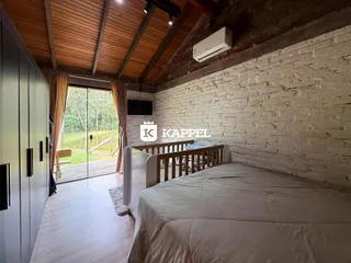 Quarto com cama de casal e parede de tijolos aparentes.