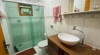Banheiro com revestimento de cerâmica e box de vidro.