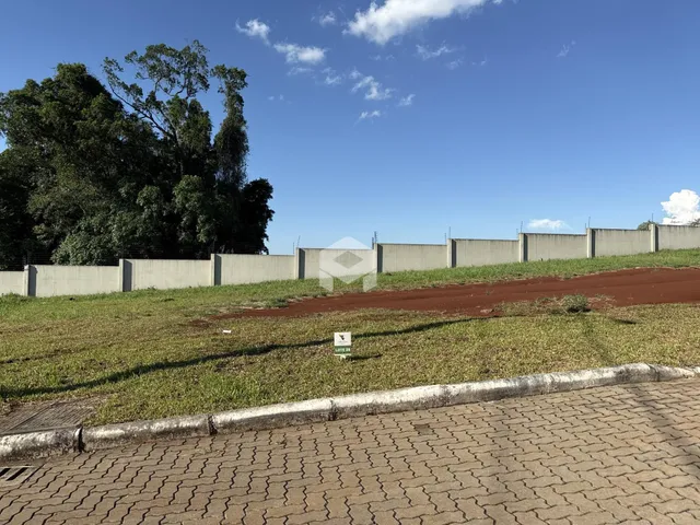 Vista externa de um muro de concreto e área gramada de uma propriedade.