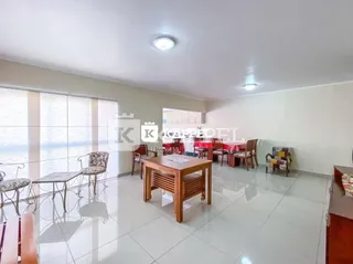 Sala de jantar com mesa e cadeiras em um ambiente claro com piso de cerâmica.