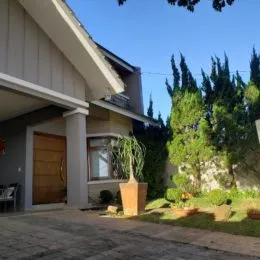 Fachada de uma residência em Lajeado, Brasil, com porta de madeira e vegetação ao fundo.