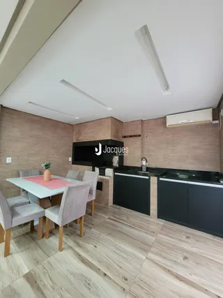 Ambiente de sala de jantar e cozinha com piso de madeira clara.