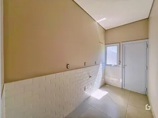 Foto de um canto de um ambiente interno com paredes bege e revestimento branco.