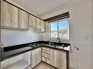 Cozinha com armários de madeira e bancada escura.