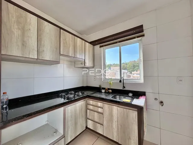 Cozinha com armários de madeira e bancada escura.