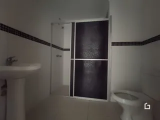 Banheiro interno com revestimento de azulejos pretos e brancos.
