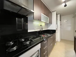 Imagem de uma cozinha moderna com armários escuros e bancadas pretas.