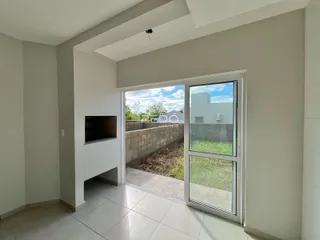 Sala de estar com porta de vidro abrindo para o quintal.