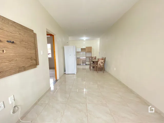 Corredor com piso de cerâmica claro que leva à área da cozinha.