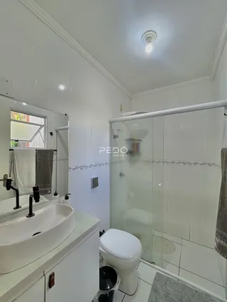 Interior de um banheiro com bancada dupla e box de vidro.