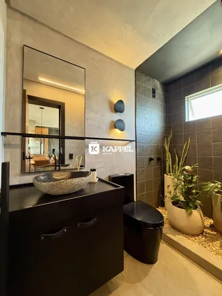 Banheiro com bancada escura e revestimento de azulejos marrons.