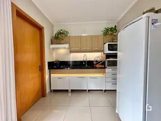 A cozinha apresenta armários de madeira e bancadas escuras.