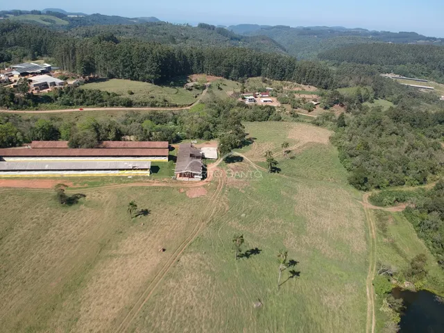 Vista aérea de uma propriedade rural com campos abertos e estruturas rurais.