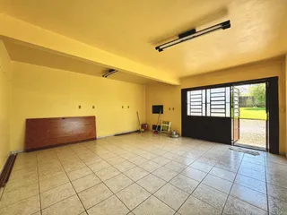 Sala ampla com piso de cerâmica e porta de vidro que dá acesso ao exterior.