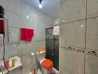 Foto de um banheiro com revestimento cerâmico e box de vidro.