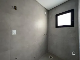 Parede interna de um ambiente com janela e revestimento cinza.