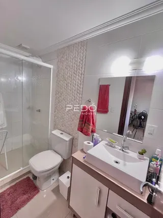 Foto do interior de um banheiro com revestimento branco.