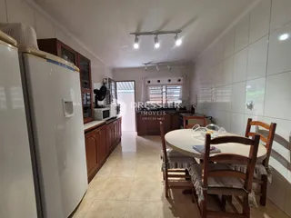 Interior de uma cozinha e sala de jantar com armários de madeira e piso de cerâmica.