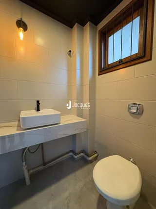 Foto de um banheiro com revestimento de azulejo branco e bancada de mármore.