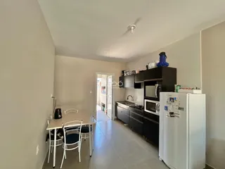 Ambiente interno de uma sala de jantar conectada à cozinha.