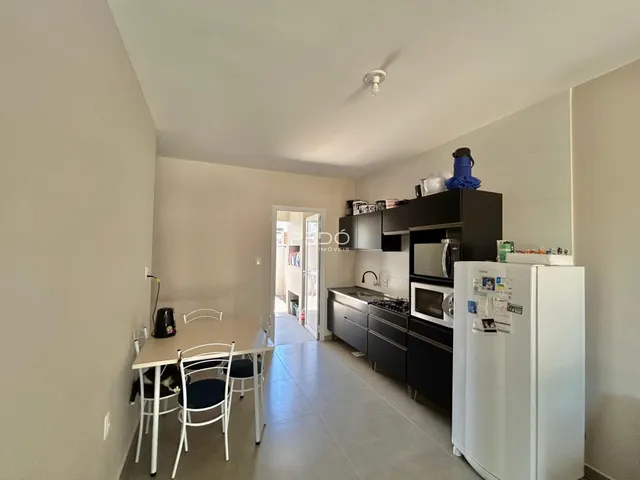 Ambiente interno de uma sala de jantar conectada à cozinha.