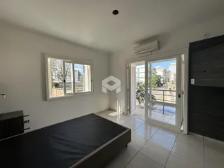 Quarto com janela e acesso a uma área externa por porta de vidro.
