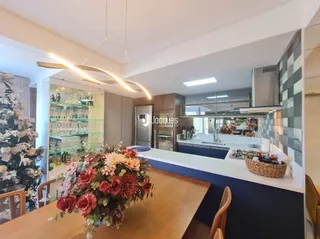Vista interna de uma cozinha com armários de madeira e bancadas brancas.