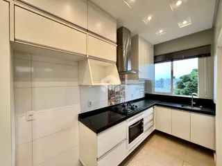 Cozinha moderna com armários brancos e bancadas escuras.