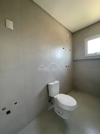 Foto de um banheiro simples com paredes claras e um vaso sanitário branco.
