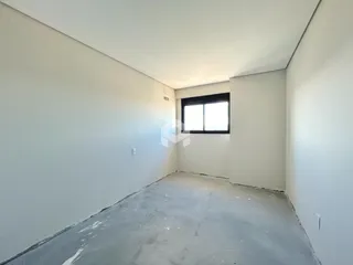 Espaço interno vazio com paredes brancas e piso de concreto.