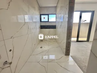 Hall de entrada com revestimento em mármore branco e porta de vidro.