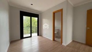 Interior de uma sala com piso de madeira e porta de vidro abrindo para uma varanda.