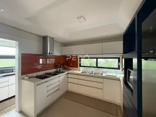 Cozinha moderna com armários brancos e backsplash vermelho em um imóvel no Brasil.