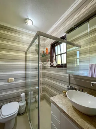 Foto do interior de um banheiro com box de vidro transparente.