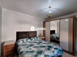 Quarto com cama grande e cabeceira escura, com armário embutido ao lado.