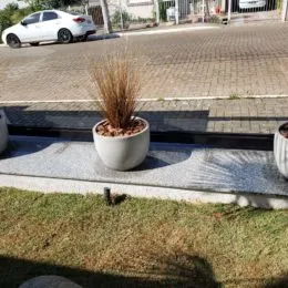 Vista externa mostrando uma área de grama e um passeio em frente a uma residência.