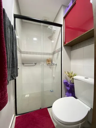 Foto de um banheiro com box de vidro e vaso sanitário.