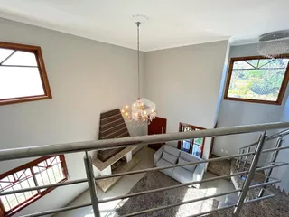 Vista interna de uma sala com grandes janelas e um lustre em um apartamento em Lajeado.