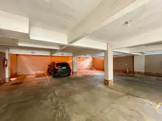 Área de garagem coberta com piso de concreto e paredes alaranjadas.