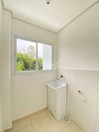 Uma parede branca com uma janela e um gabinete de pia branco em um ambiente interno.