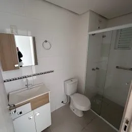 Foto de um banheiro interno mostrando uma pia e um vaso sanitário brancos.