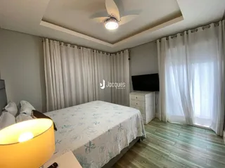 Quarto com cama e cortinas brancas.