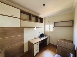 Quarto com cabeceira de madeira e escrivaninha em um ambiente interno.