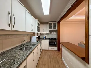 Vista interna de uma cozinha com armários brancos e bancada de granito.