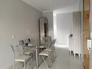 Uma sala de jantar com mesa de vidro e cadeiras metálicas em um imóvel no Brasil.