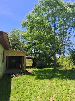 Vista externa de uma casa de madeira em Lajeado, Brasil, cercada por grama e árvores.